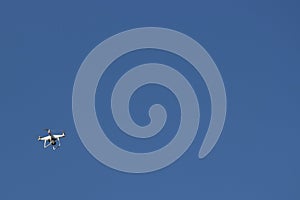 White flying dron with camera on blue sky background photo