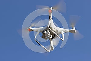 White flying dron with camera on blue sky background photo