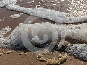 White foam on the sea shore, texture, abstract water reflections