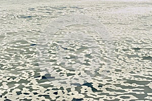 White foam on an still ocean water surface.