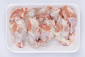 A white foam tray of raw chicken drumsticks from supermarket on