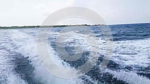 White foam water trail behind the motor boat in the Indian ocean. Fast boat ride from the island in Maldives. Splash from waves on