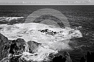 White foam of the waves crashing on the volcanic rock groynes in the Atlantic Ocean Madeira, Portugal