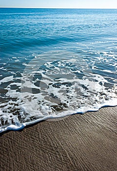 White foam from waves on a pebble sandy beach on Catalina Island in the Pacific Ocean, California