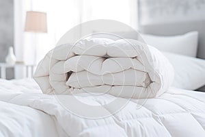 White folded duvet lying on white bed background. Preparing for winter season, household, domestic activities, hotel or