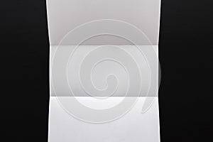 White folded sheet of paper on black background