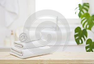 White folded towels on wooden table top in blurred bathroom