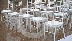 White folding chairs at the wedding ceremony with drops from the rain. Wet seat in the open air