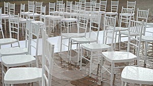 White folding chairs at the wedding ceremony with drops from the rain. Wet seat in the open air