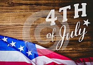 White fourth of July graphic against wood table and american flag