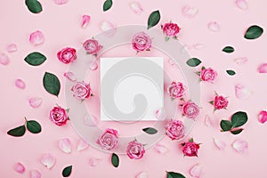 White frame blank, pink rose flowers and petals for spa or wedding mockup on pastel background top view. Beautiful floral pattern.