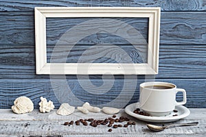 White frame, coffee cup and shells on a background of blue board