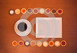 White frame, cup of coffee and assortment of mixed biscuits