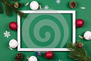 White frame with fir branches and New Year`s toys on a green background