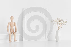 White frame mockup with books, manikin and a gypsophila in a vase on a white table.Portrait orientation