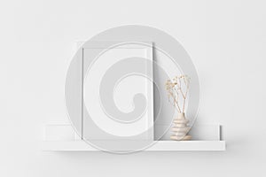 White frame mockup with a gypsophila decoration on the wall shelf