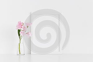 White frame mockup with pink oleander in a glass vase on a white table.Portrait orientation