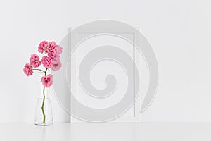 White frame mockup with pink roses in a glass vase on a white table.Portrait orientation