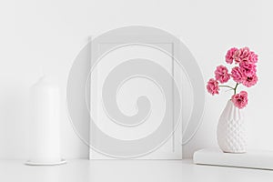White frame mockup with pink roses in a vase and candle on a white table.Portrait orientation