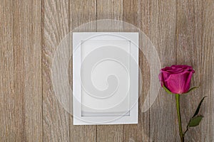 White frame mockup on rustic wooden board with pink rose