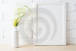 White frame mockup with wild grass ears near painted brick wall