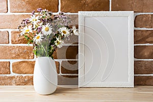 White frame mockup with wildflowers bouquet near exposed brick w