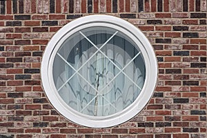 White framed circular window set in a red brick wall