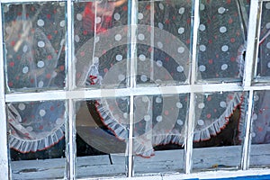 White framed glass window with colored spotted curtains