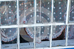 White framed glass window with colored spotted curtains