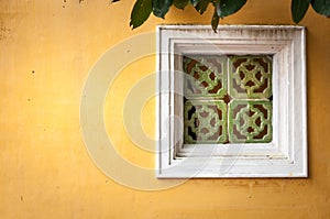 White framed window on wall of yellow stucco.