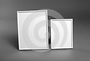 White frames for paintings or photographs on gray background.