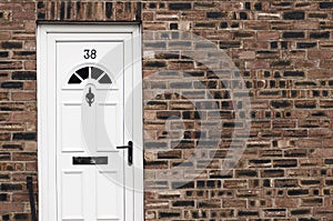 White front door of a red brick English town house. Manchester.