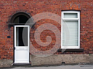 White front door and window of a typical old brick british terraced house with white windows and blinds