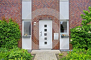 White front door with windows in a private residential brick house in Germany