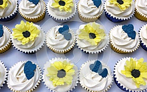 White frosted cupcakes with sunflowers and blue hearts