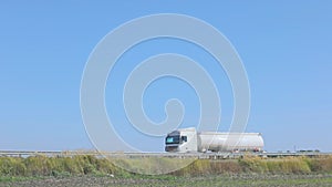 White fuel truck driving along the highway. A fuel truck drives on the highway in good weather