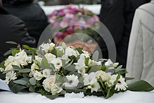 White Funeral flowers in the snow before a caket