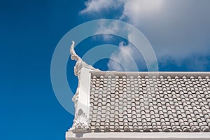 White gable apex on blue sky with cloud