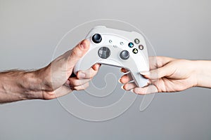 White gamepad in the hands of two people