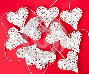 White garland in the shape of a heart on a red background. Concept of Valentine`s day or wedding. Flatlay composition. Top view