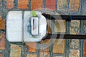 White gas meter on the brick wall of the building