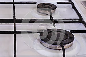 On the white gas stove the burner is lit from which the flame of natural gas is visible