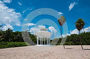 White gazebo on a beach with palm trees