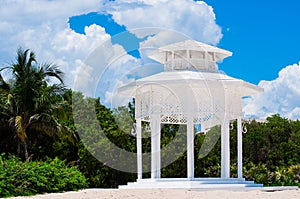 White gazebo on a beach with palm trees