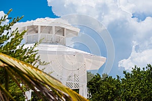 White gazebo on a beach with palm trees, blue sky background