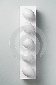 White ggs in a row on gray background