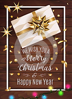 White gift box with a beautiful gold bow on wooden background. Merry Christmas and Happy New Year greeting card. Vintage