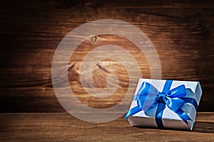 White gift box with blue ribbon on vintage wood