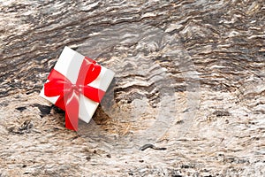 White gift box with perfect red ribbon bow on wooden table background in top view with copy space.