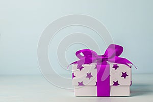 White gift box with purple star pattern and purple ribbon bow